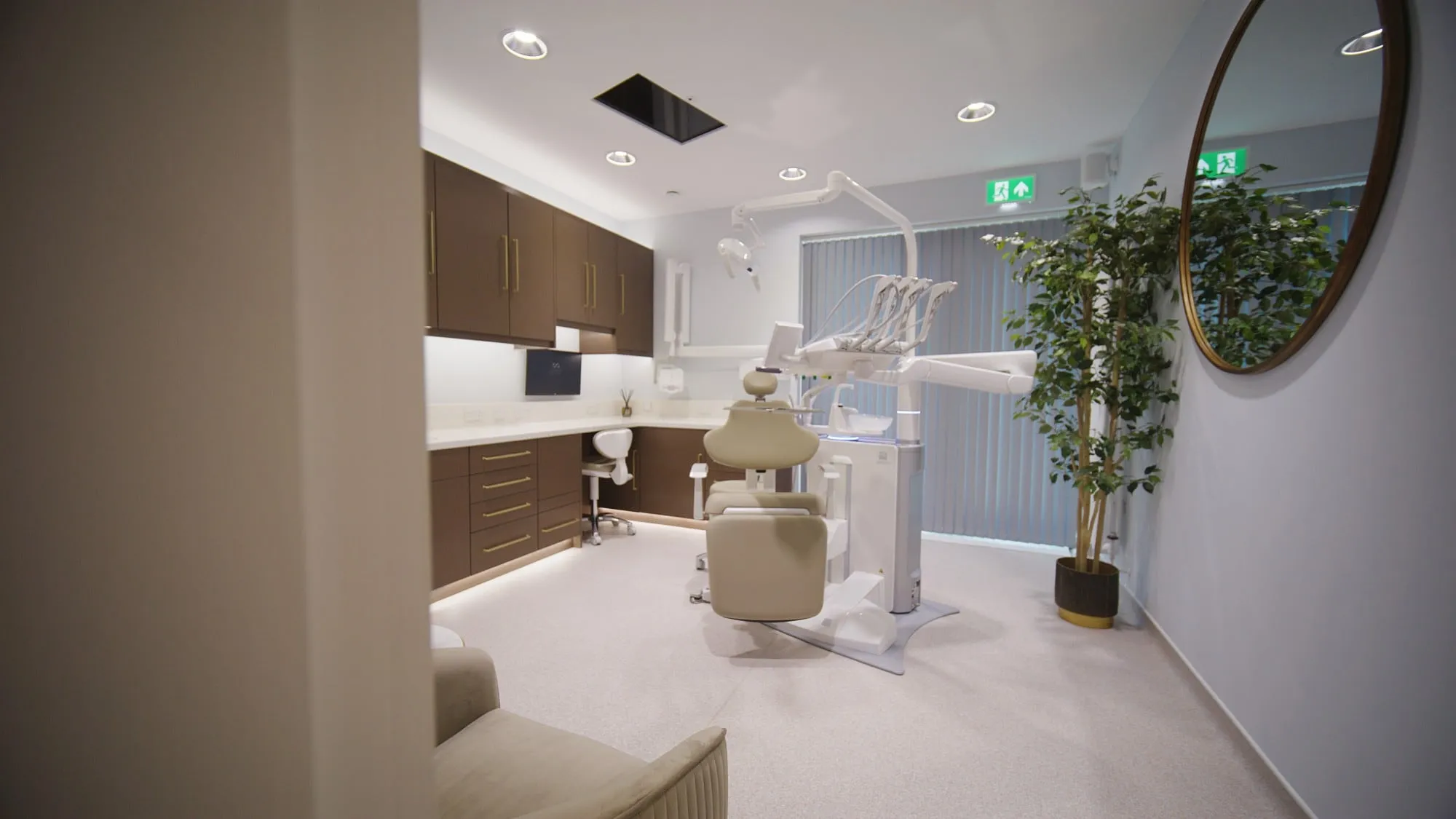 Surgery with walnut cabinetry, round gilt mirror and ceiling screen at Infinity Dental Suite, Harrogate
