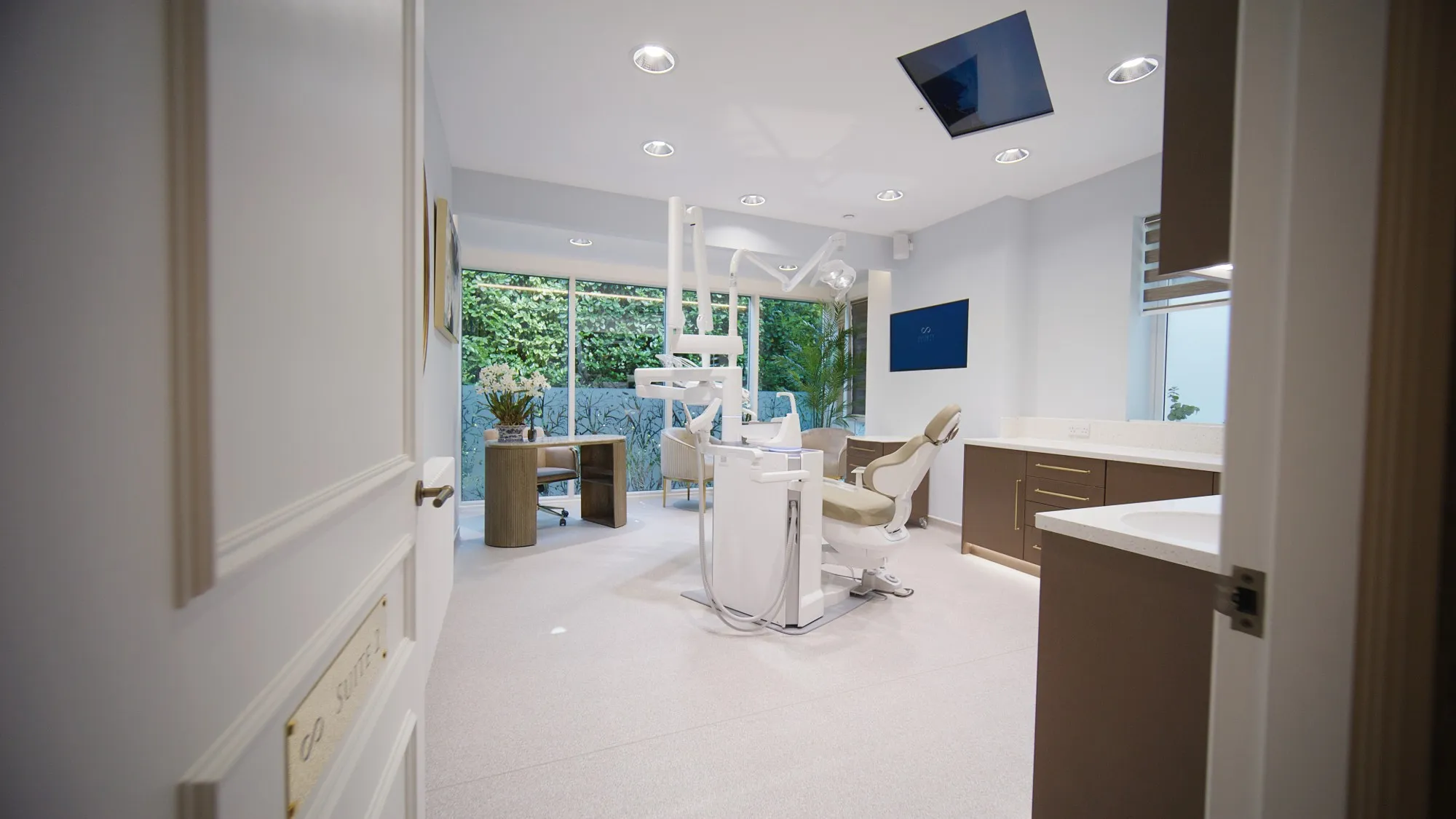 Surgery suite with full-height garden windows and walnut cabinetry at Infinity Dental Suite, Harrogate